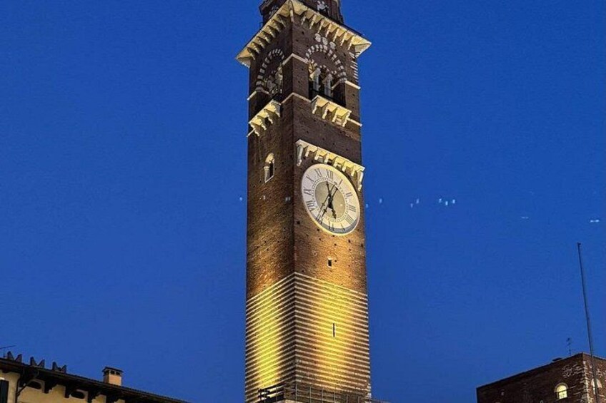 Ein hoher Glockenturm mit einer goldfarbenen Uhr, vor einem strahlend blauen Himmel. 4
