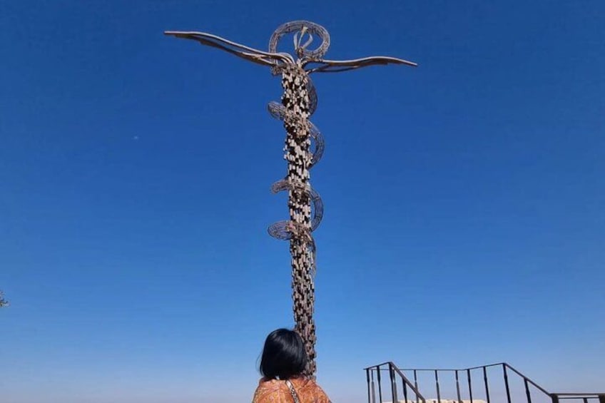A tall, abstract sculpture with a spiral design and a figure at the top, set against a clear blue sky. 2