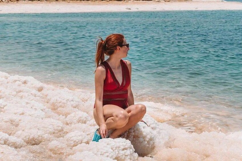Una persona sentada en una playa arenosa con aguas azules cristalinas al fondo. 4