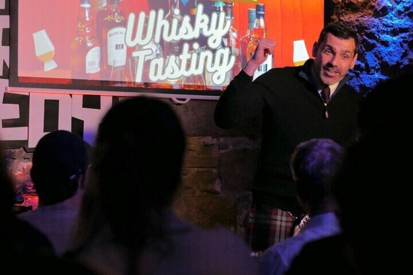 A person presenting in front of a 'Whisky Tasting' sign. 4