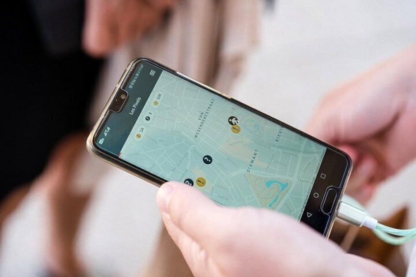 Une personne tient un smartphone sur lequel est ouverte une application de cartographie, affichant un lieu marqué par une punaise jaune. 5
