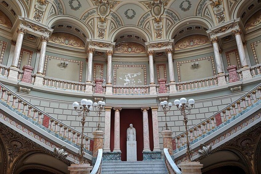 Una imponente escalera con barandales y columnas decorativas, que conduce a un amplio acceso. 5