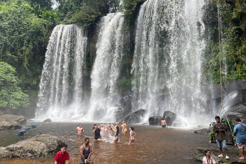 A waterfall with people swimming in the water. 4