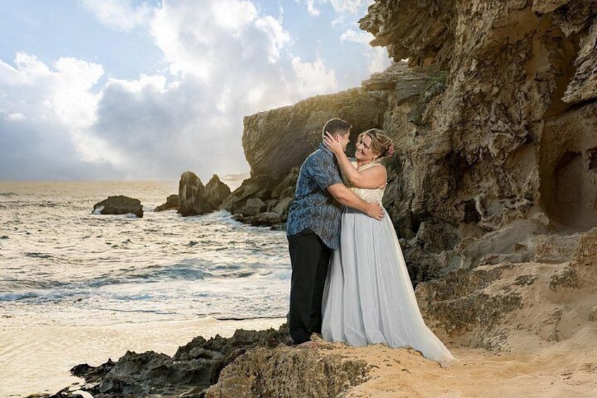 Una pareja se abraza en una playa rocosa con el océano al fondo. 5