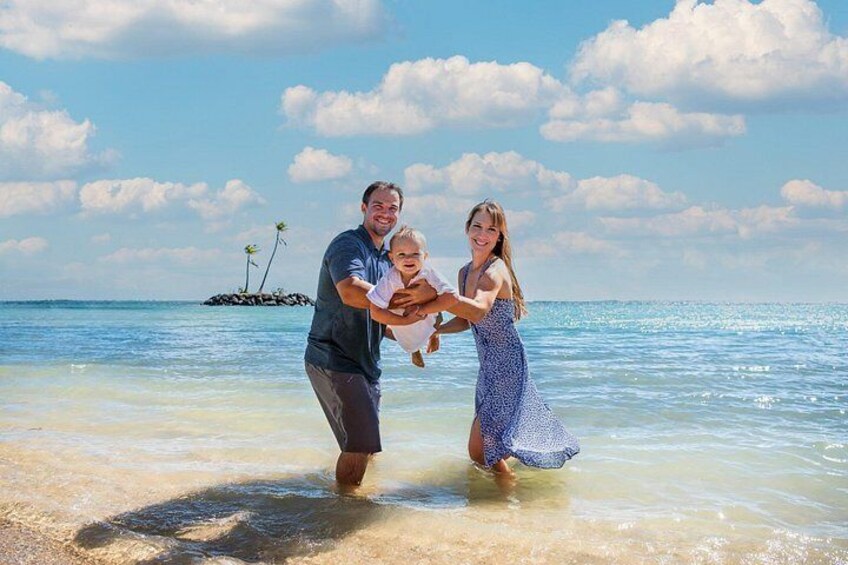Una familia en la playa, con agua cristalina y una pequeña isla al fondo. 4