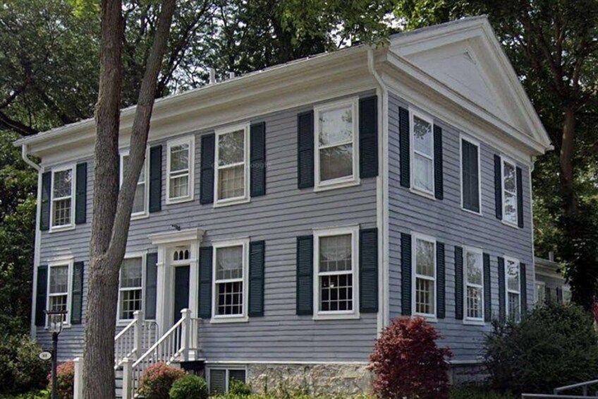 A two-story house with a gabled roof, white trim, and dark shutters. 5