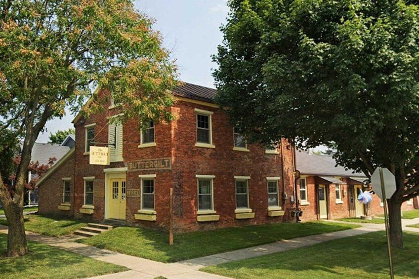 A brick building with a sign reading 'BUTTERGILT' and a sidewalk in front. 3