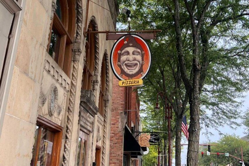 A pizzeria sign on a building with ornate architecture and an American flag. 2