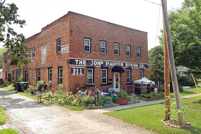 A brick building with a sign reading 'The John Pausen Broom Co.' and a number '311' on the side. 4