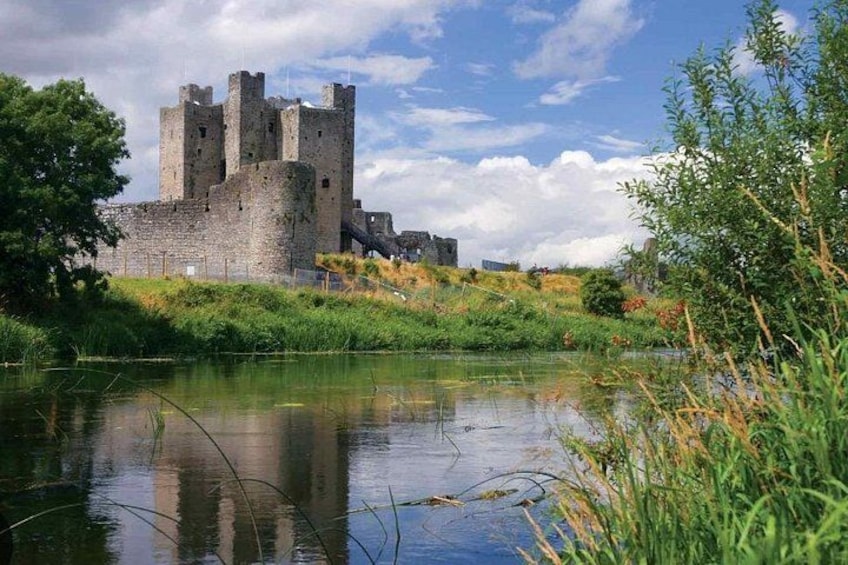 Un castillo junto a un río tranquilo, con abundante vegetación y cielo despejado. 3