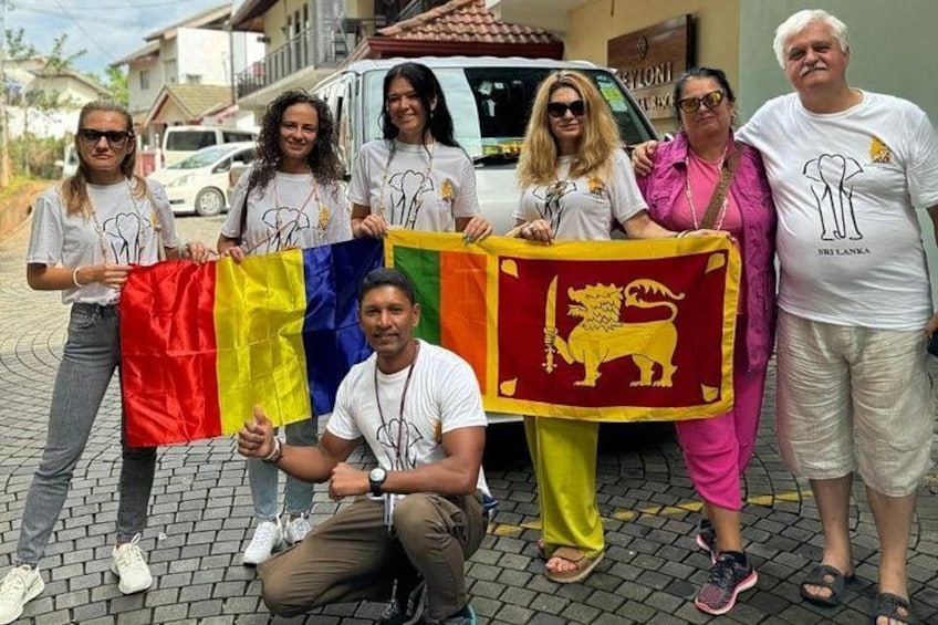 A group of people holding flags, standing on a paved surface with buildings in the background. 1