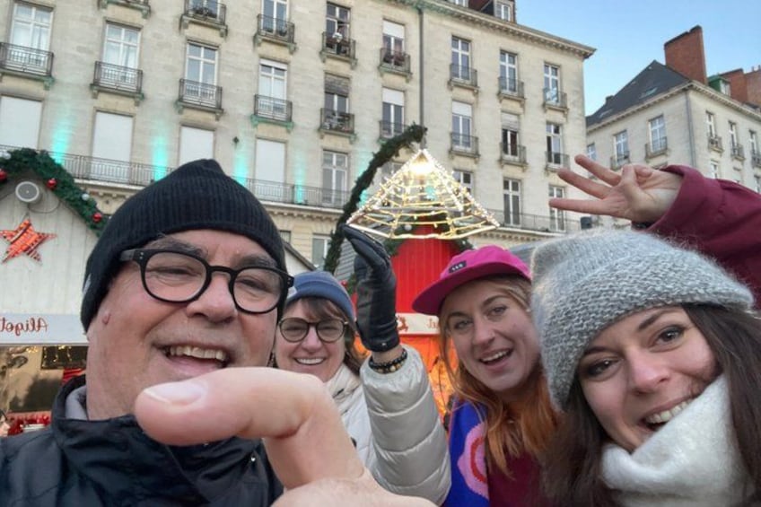 A group of people in winter clothing, a building with balconies, and a Christmas tree. 2