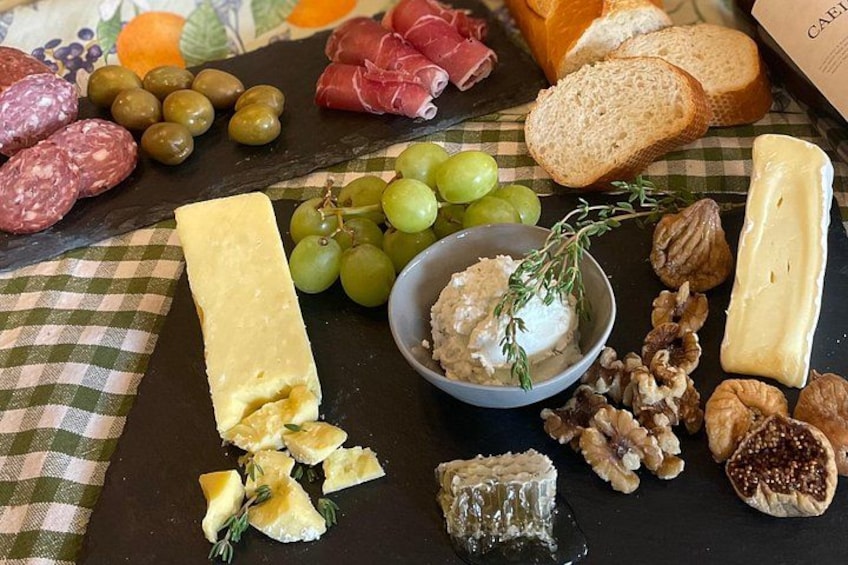 Una tabla de fiambres con varios quesos, embutidos, uvas, nueces y pan. 2