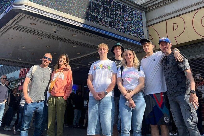 A group of people standing in front of a building with a large sign. 2