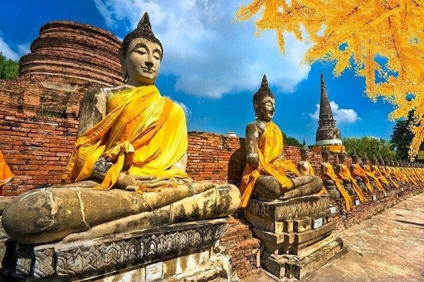 Una hilera de grandes estatuas de Buda en un templo, bajo un cielo azul claro. 2