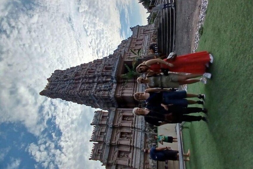 A group of people standing in front of a large, ornate building with intricate carvings. 1