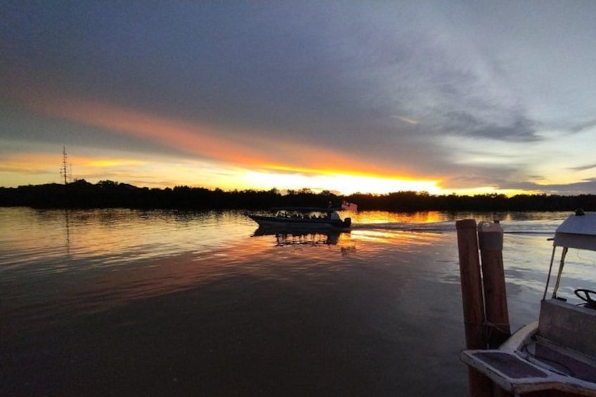Un coucher de soleil sur un lac paisible, avec des bateaux, un quai et une ligne électrique éloignée. 2