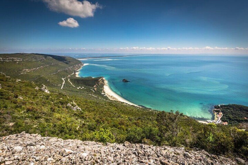 Un paisaje costero con mar azul cristalino, una playa arenosa y colinas verdes. 5
