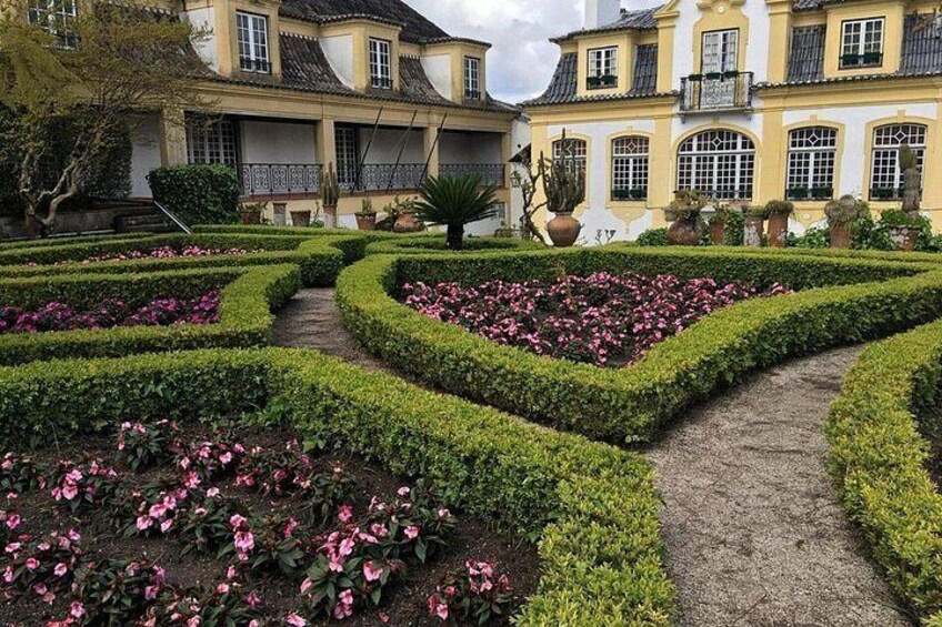 Jardín formal con setos geométricos y flores rosas, rodeado de arquitectura clásica. 4