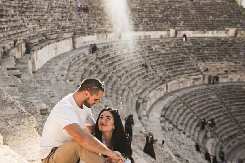 An ancient amphitheater with stone seating and a central stage. 3