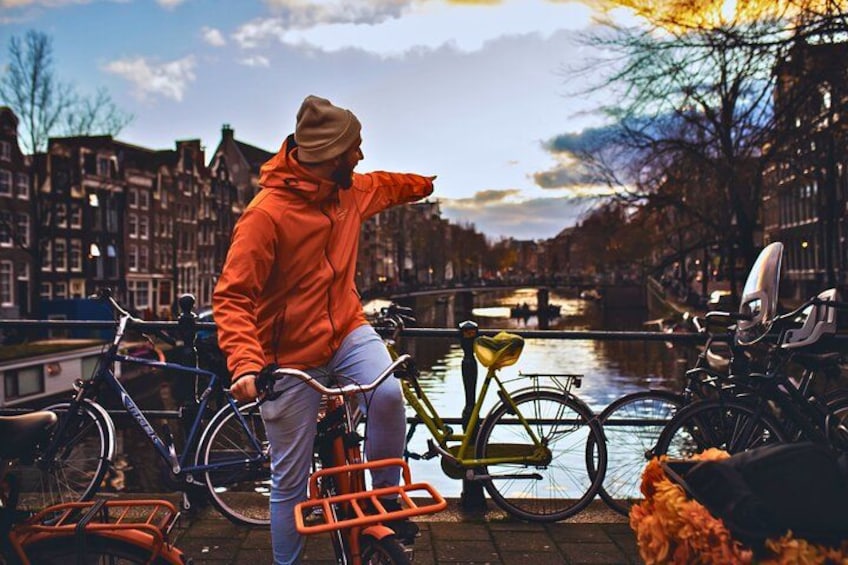 A person on a bicycle in a canal-side setting with bicycles and a dog nearby. 5