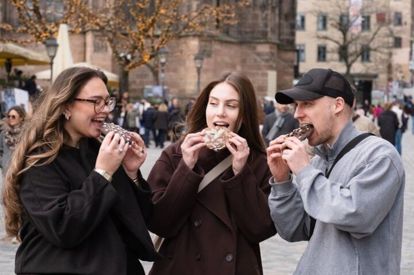 Tre personer spiser is i et udendørs bymiljø. 2