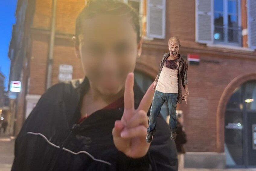 En person peger på en zombiefigur foran en bygning. 4