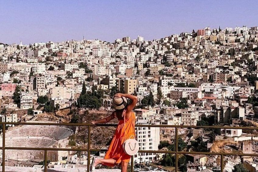 Une personne vêtue d’une robe rouge se tient sur un balcon d’où l’on a une vue imprenable sur une ville tentaculaire. 3