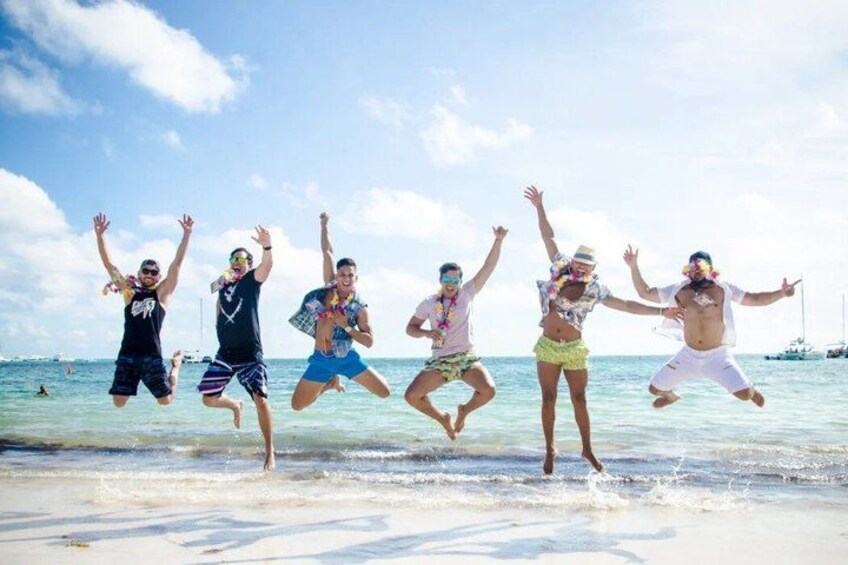 A group of people jumping on a beach with the ocean and a clear sky in the background. 4