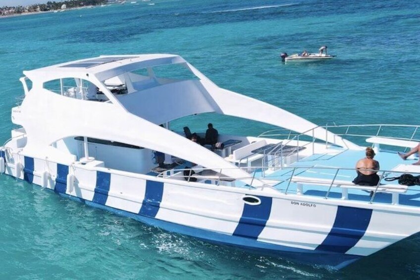 A white and blue boat with 'DON AGOLFO' written on the side, floating on turquoise water. 5