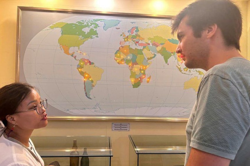 A person standing in front of a world map with a globe and a display case. 3