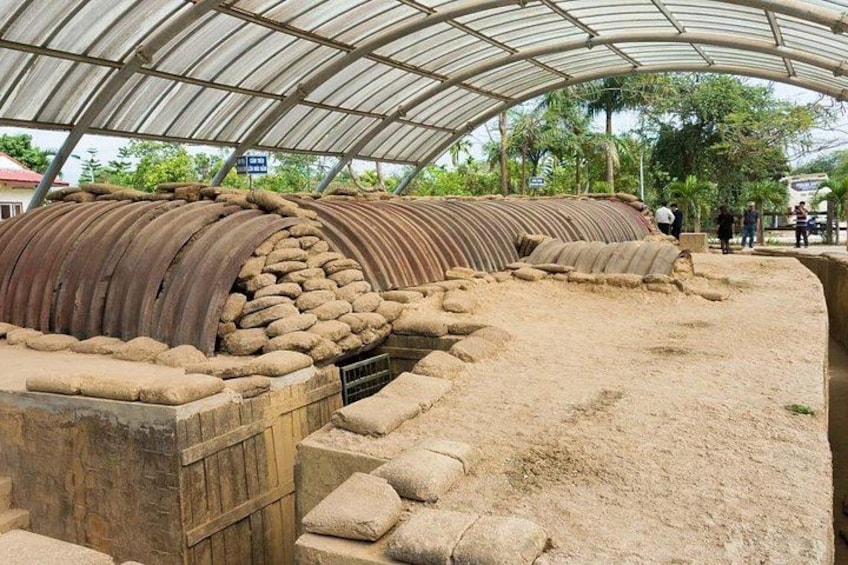An archaeological site with ancient stone structures and a metal roof. 5