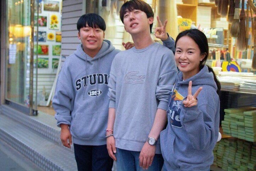 Three people standing in front of a store with a display of goods. 5