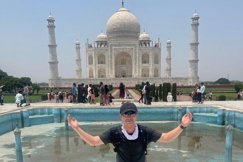 Eine Person steht mit ausgestreckten Armen vor dem Taj Mahal. 3