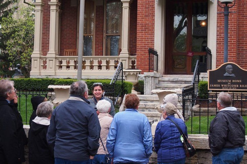 Een groep mensen staat voor een gebouw met een plaquette waarop staat 'Museum Home of James Whitcomb Riley'. 2