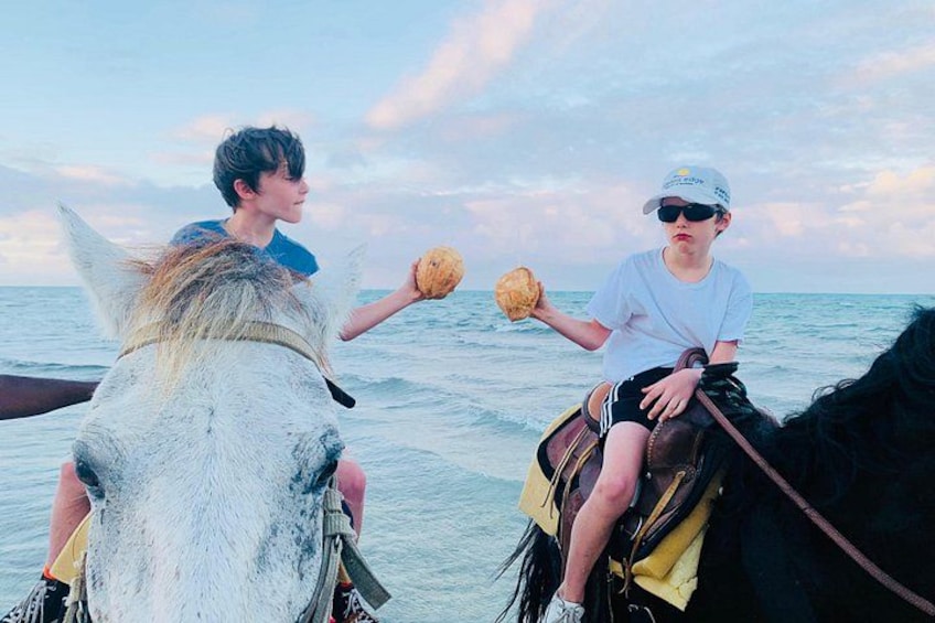 Two people riding horses on a beach with the ocean in the background. 5