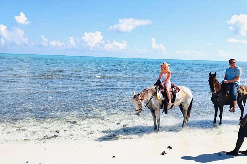 Two people riding horses on a beach with the ocean in the background. 4