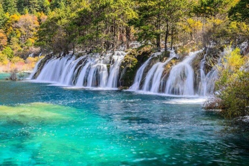 A waterfall cascading into a turquoise pool surrounded by trees. 2