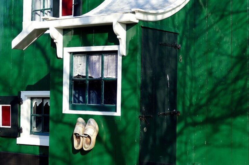 Un edificio verde con una ventana y una puerta, y un par de zapatos colgados en la pared. 2