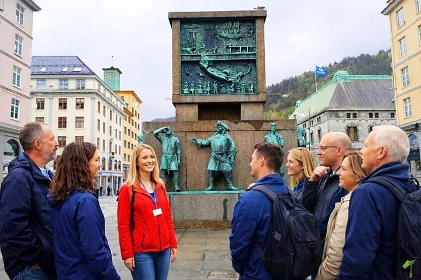 A group of people standing in front of a historical monument with statues. 1