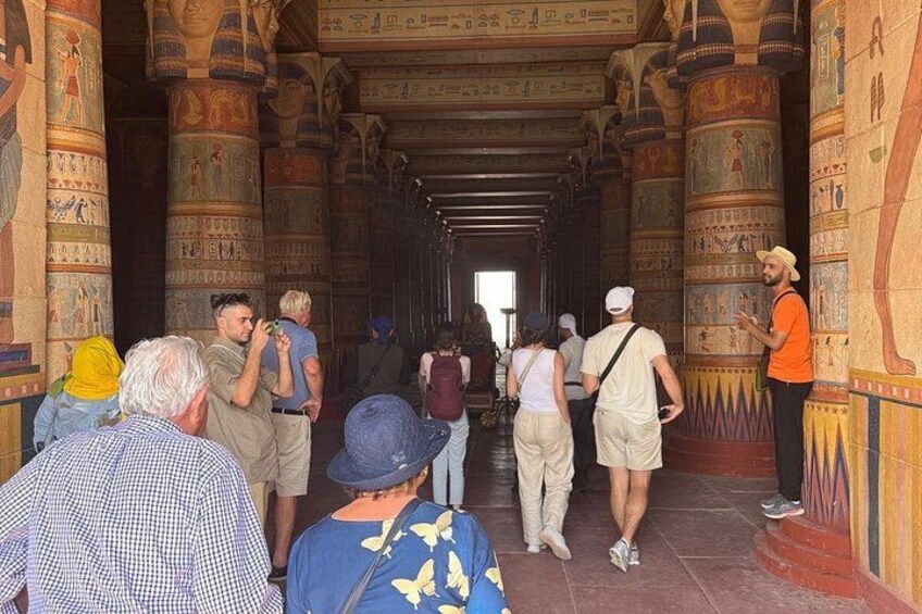 A group of tourists walking through an ancient Egyptian temple with hieroglyphs on the walls. 4