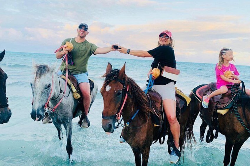 Drie personen ríijden paard aan het strand, met de oceaan op de achtergrond. 5