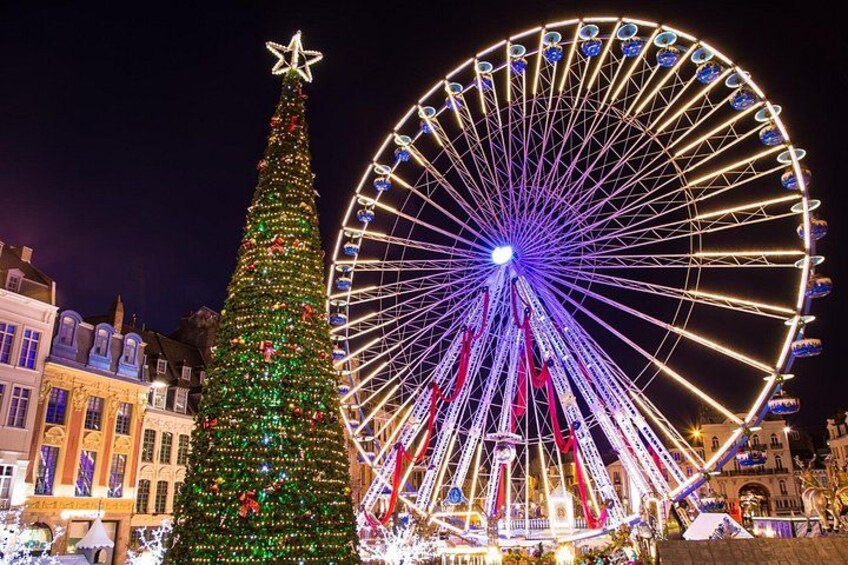 A large Ferris wheel and a decorated Christmas tree in an urban setting. 4