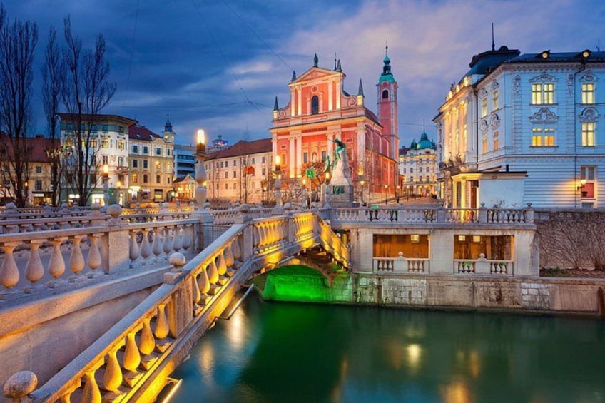 A bridge over a river with buildings on either side, including a prominent pink and white church. 2