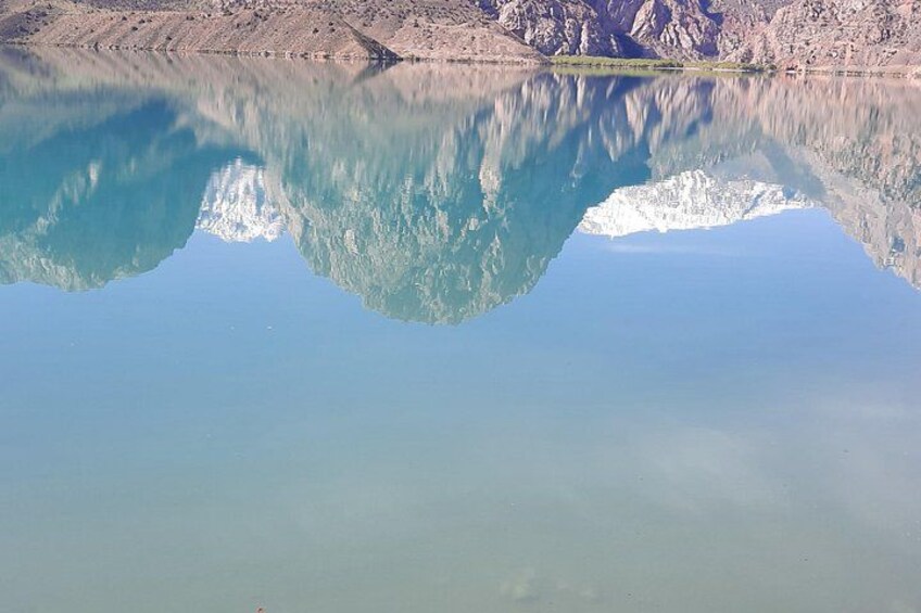 Een kalm meer met heldere weerspiegelingen van bergen en een besneeuwde bergtop. 2