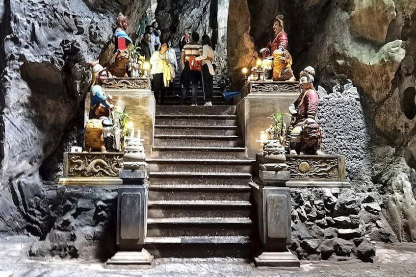 Ett tempel som är inbyggt i en grotta, med en trappa som leder upp till en plattform, vilken är utsmyckad med statyer och offergåvor. 2