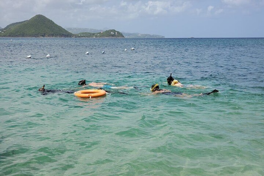 People swimming in the ocean with a buoy and a distant island. 2