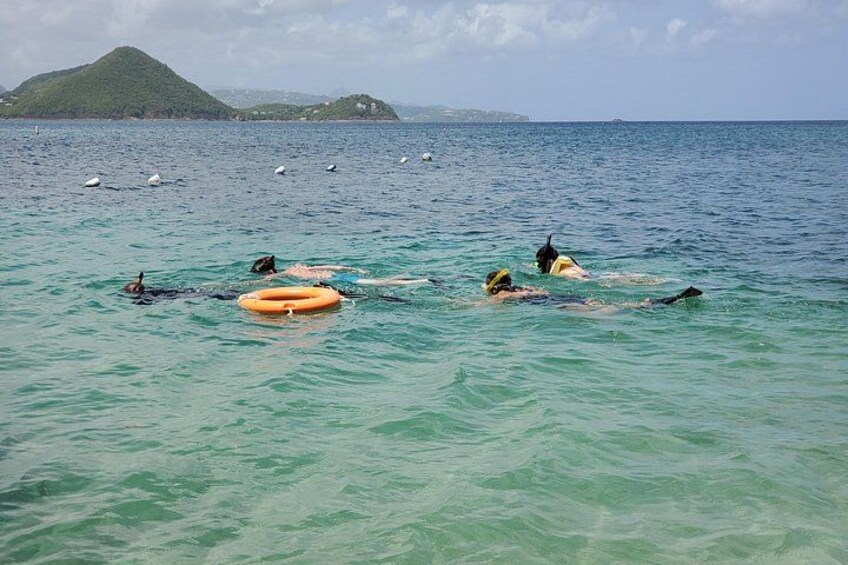 People swimming in the ocean with a buoy and a distant island. 4