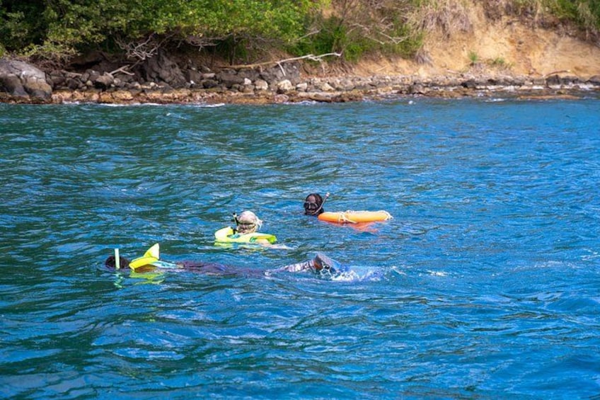 Three people swimming in a body of water with surfboards. 2