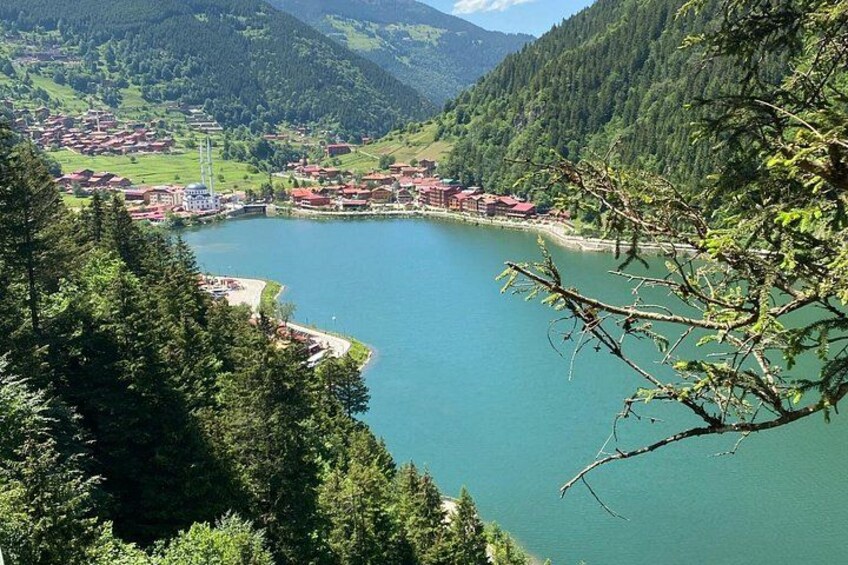 A lake surrounded by forested hills and a small town with red-roofed buildings. 2